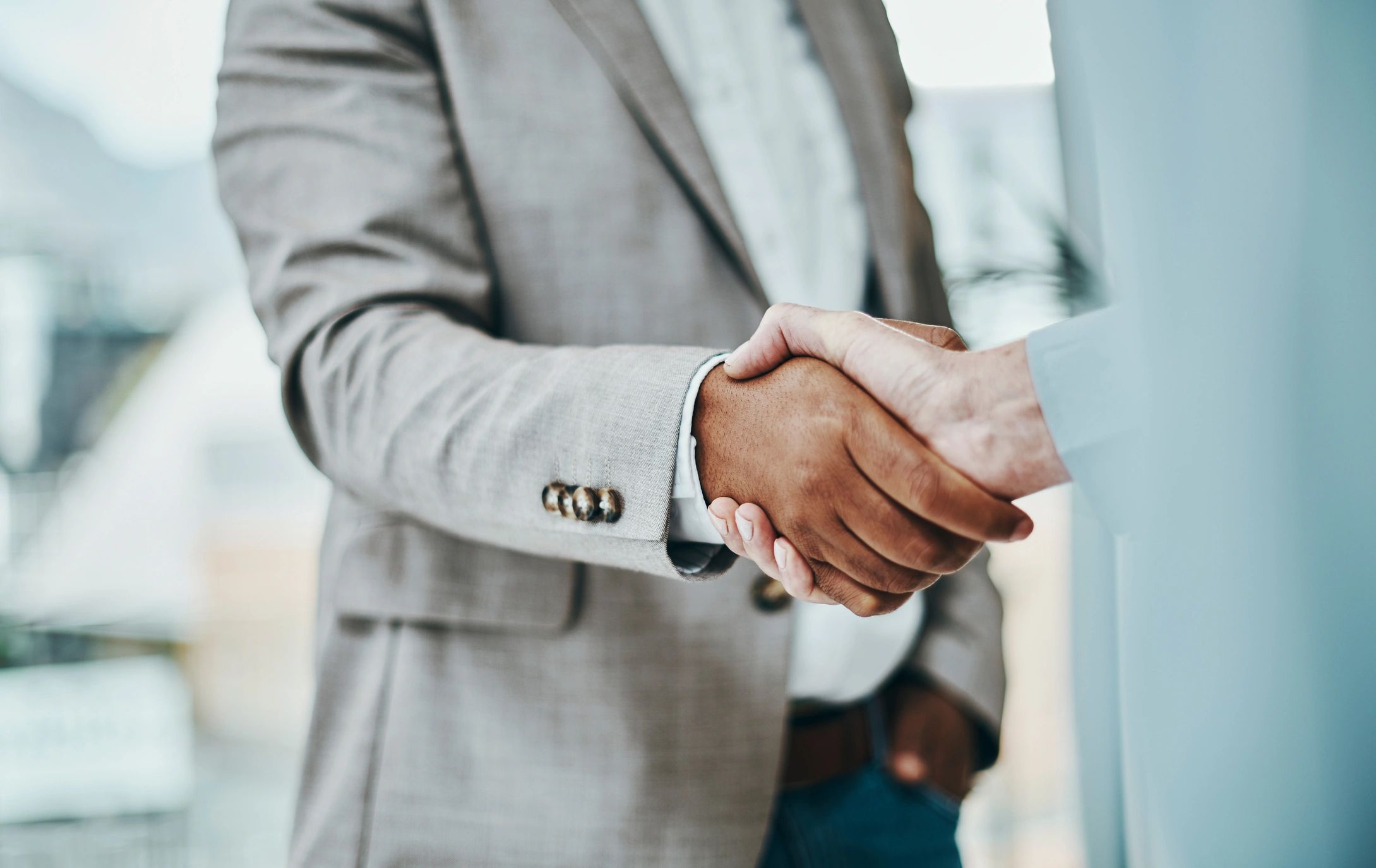 Two professionals shaking hands over property documents