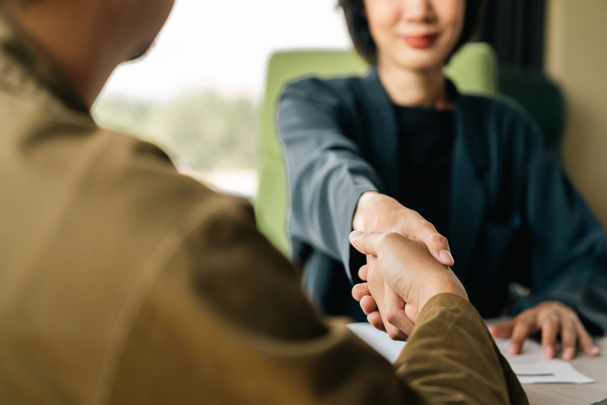 Close-up of two Asian professionals shaking hands, symbolizing a successful agreement